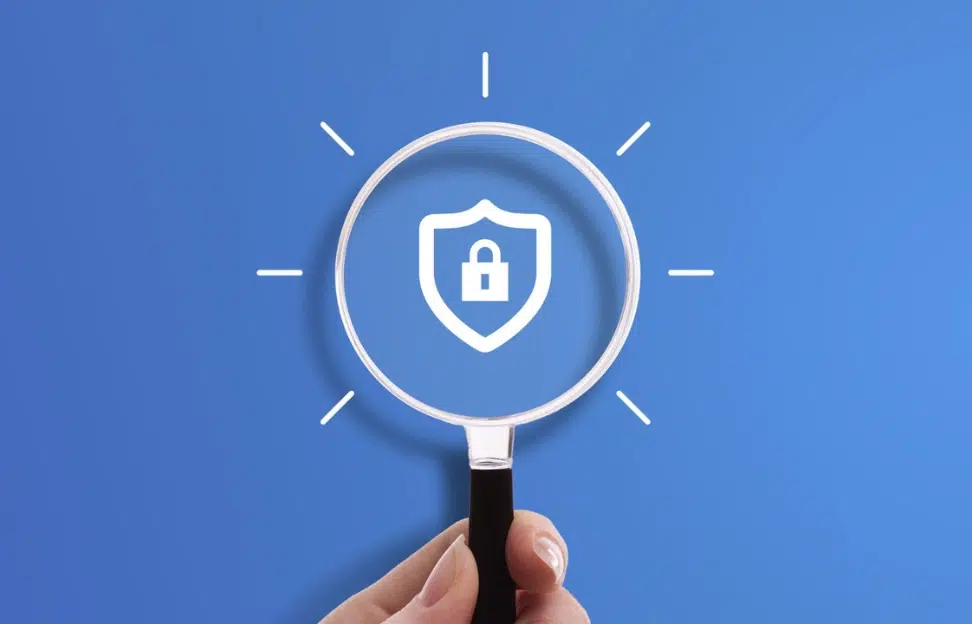Hand holding magnifying glass with locked shield icon symbol of cybersecurity secure connection